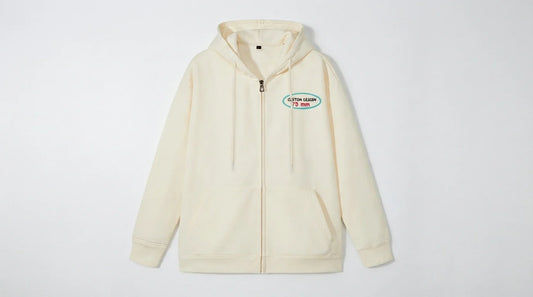 Full-zip hoodie hanging against white background showing zipper and fabric texture.